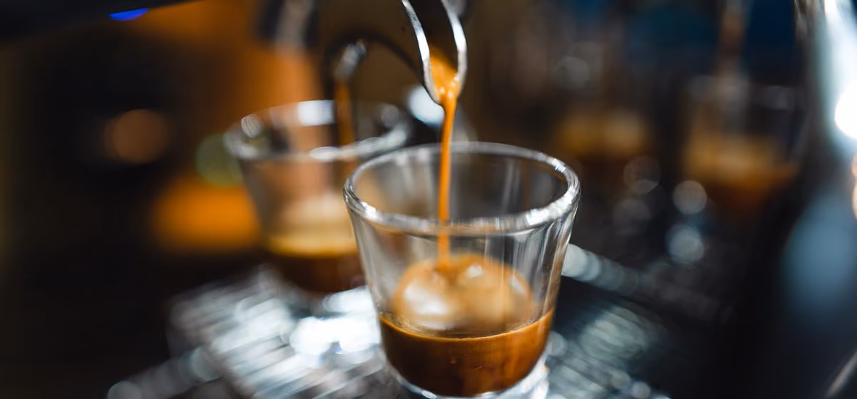 Espresso pouring into a glass cup.